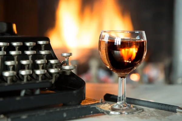 Glass of wine, typewriter and a fireplace — Stock Photo, Image