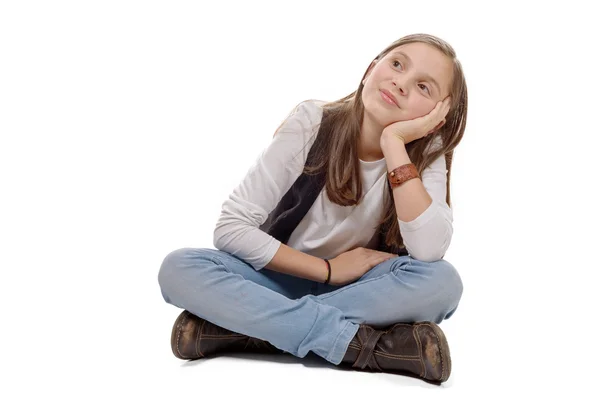 Pequena menina pensativa sentado de pernas cruzadas em um fundo branco — Fotografia de Stock
