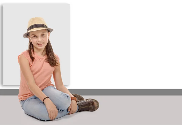 Ragazza in jeans, stivali, cappello e t-shirt seduta sul pavimento — Foto Stock