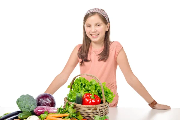 Lachende jong meisje permanent achter een stapel groenten — Stockfoto