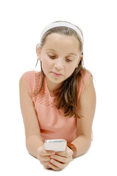 Sorridente bambina sdraiata sul pavimento con telefono sulla schiena bianca — Foto Stock