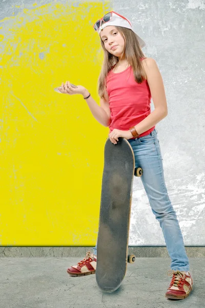 Jolie petite fille avec skateboard et téléphone portable — Photo