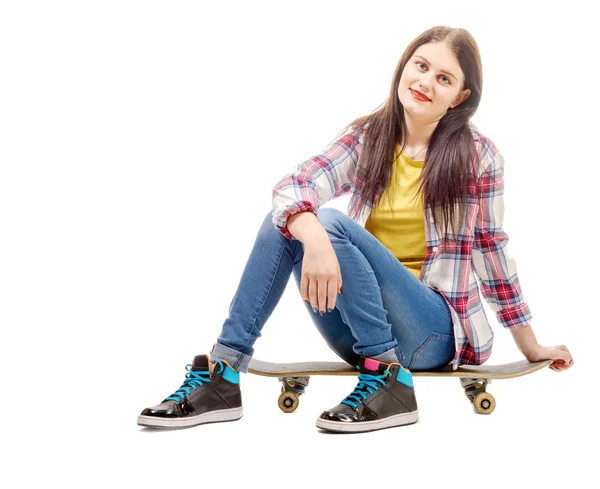 Belle jeune femme posant avec une planche à roulettes, assise sur patins — Photo