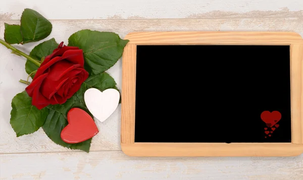 Červená růže a černá břidlice na dřevo pozadí — Stock fotografie
