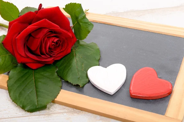 Red rose and black slate on a wood background — Stock Photo, Image