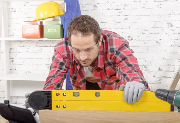 Young man viewing a spirit level,  to read the position of the — Stock Photo, Image