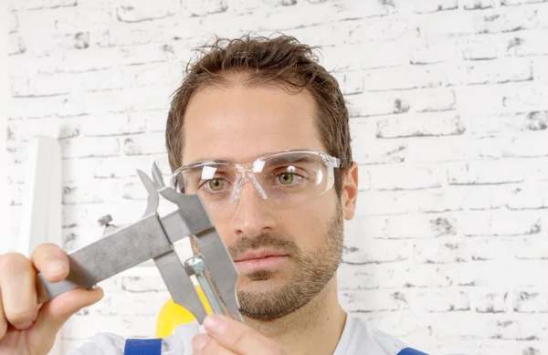 캘리퍼스를 사용 하 여 나사를 측정 하는 젊은 남자 — 스톡 사진