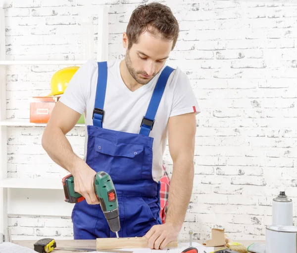 Gat boren in de plank in zijn werkplaats timmerman — Stockfoto