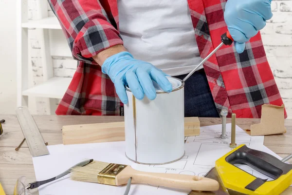 House painter opens a can of paint with a screwdriver — Stock Photo, Image