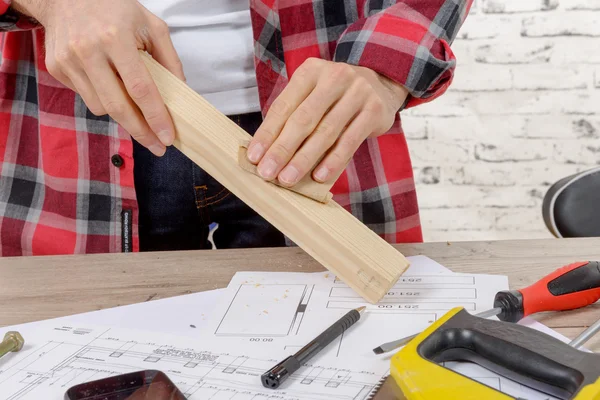 Jonge timmerman schuren van een houten plank — Stockfoto