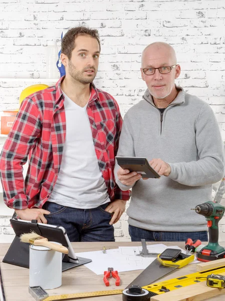 Two workers looking at calculator in  studio — Stock Photo, Image