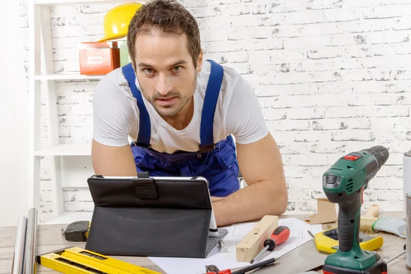 Jovem sorrindo usando o tablet para DIY — Fotografia de Stock