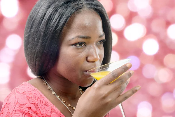 Bella donna africana bere succo d'arancia, bokeh su backgrou — Foto Stock