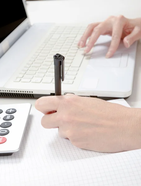 Mão feminina com caneta, notebook e calculadora na área de trabalho — Fotografia de Stock