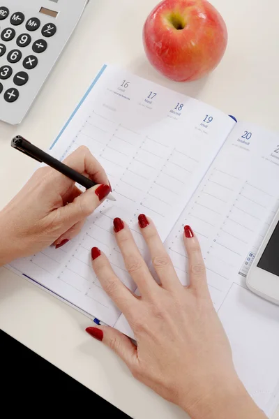 Primo piano della mano della donna che scrive sull'organizzatore — Foto Stock