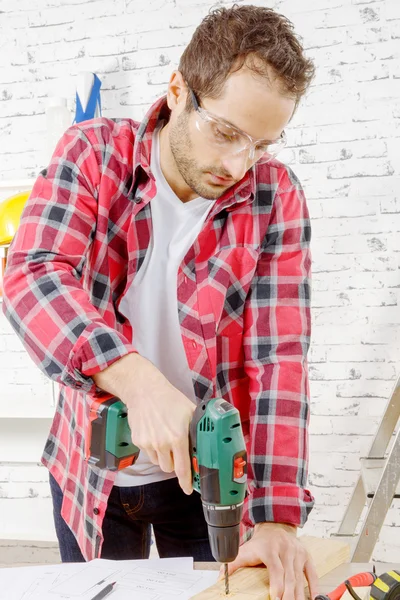 Gat boren in de plank in zijn werkplaats timmerman — Stockfoto