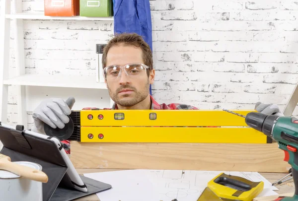 Young man viewing a spirit level,  to read the position of the b — Stock Photo, Image