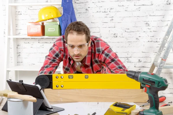 Junger Mann, der eine Wasserwaage betrachtet, um die Position der — Stockfoto