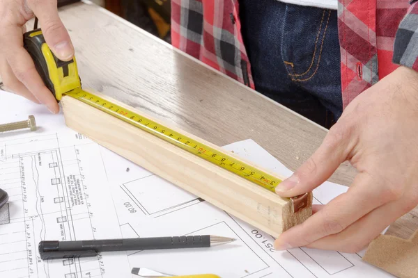 Young man measuring wooden board — Stock Photo, Image