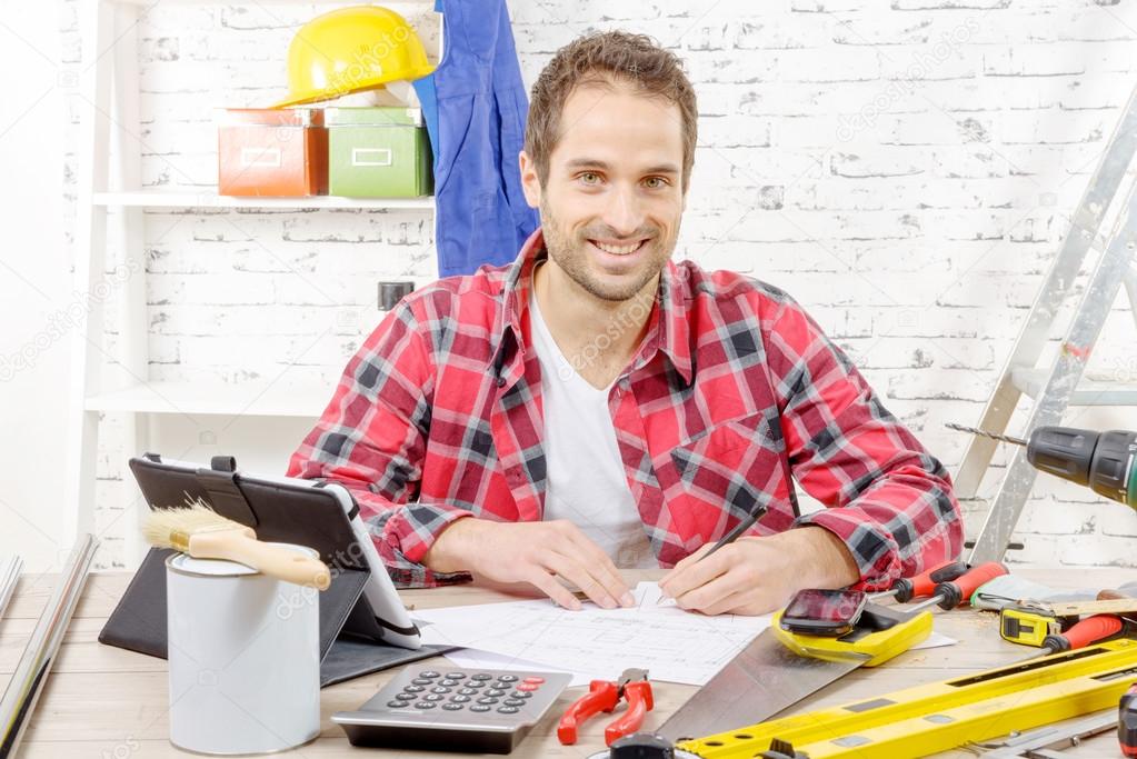 smiling carpenter sitting at the desk, in his studio