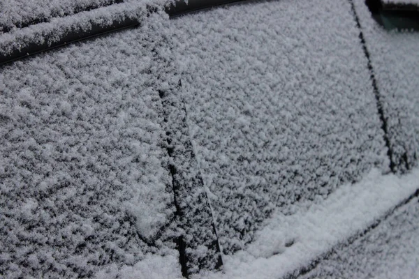 Cars under the snow after a snowfall. There is a lot of snow on the roofs, windows and hoods of cars. Large snowdrifts on the street. Cars in a snow-covered parking lot. Cold snowy winter weather.