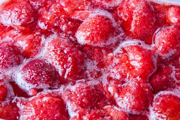 Cooking strawberry jam, red background of strawberry jam. Strawberry berries in jam.