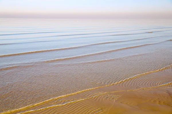 Sfondo con mare surf piccole onde sulle acque poco profonde del Mar Baltico a Jurmala in morbida luce rosa del sole al tramonto — Foto Stock