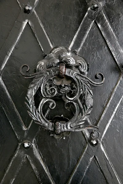 Forgé avec tourbillons vieille poignée en métal sur la porte en métal sombre d'un vieux château — Photo