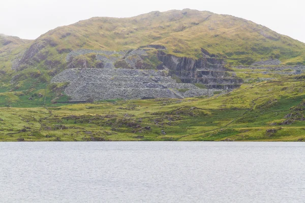 Cwmystradllyn Slate Quarry sulla collina, lago in primo piano . — Foto Stock