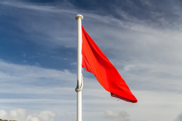 Bandera roja contra el cielo azul — Foto de Stock