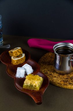 Türk Lokumu ve Baclava, fincanlı, çay tabağı ve su bardağıyla birlikte Türk kahvesi ile servis edilir. Düşük ışıklandırma, portatif, en üstte telif alanı.