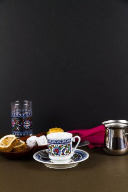 Fincanlı Türk kahvesi, çay tabağı, su bardağı Türk lokumu ve Baclava ile servis ediliyor. Düşük ışıklandırma. Tepede telif alanı, portre.
