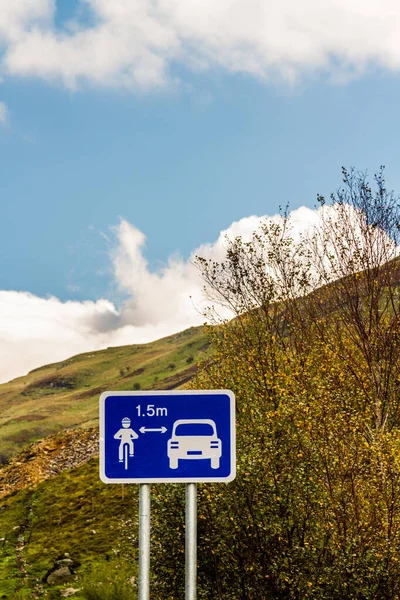 Sign in country of UK Wales. Showing car keeping 1.5 metres from cyclist, portrait, copyspace at top.