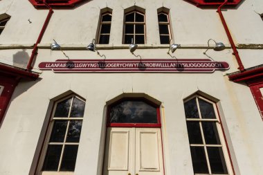 Llanfair Pwyngyll Llanfair Pwllgwyngyll ya da Llanfair pwygwyngyllgogerychwyrndrobwllllantysiliogogogogogogoch tabelasını tren istasyonuna asar. Anglesey, Galler, manzara, geniş açı