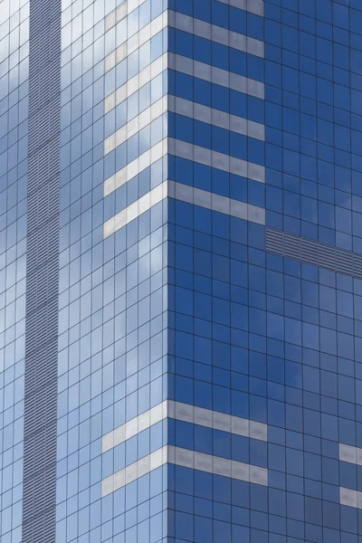 Grattacielo di vetro con cielo blu e nuvole riflesse nelle finestre . — Foto Stock