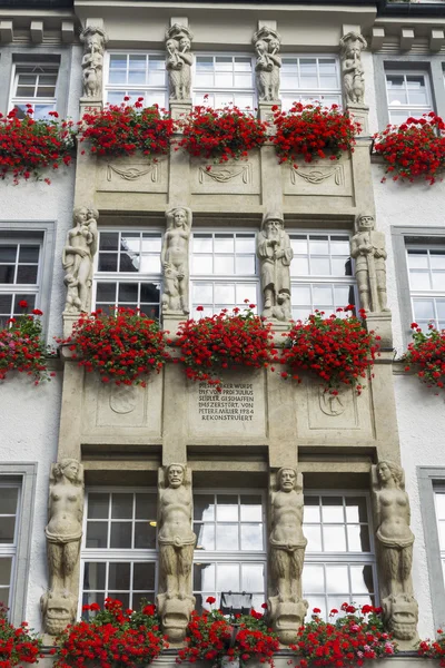 Windows with red geranium boxes an statues. Munich, Germany. — Stock Photo, Image