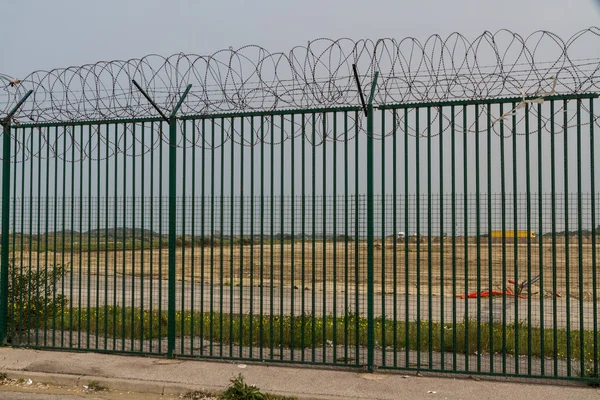 Zelený plot s ostnatý drát střeží francouzské trajektového terminálu. — Stock fotografie