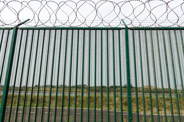 Groene hek met scheermes draad Franse veerboothaven bewaken. — Stockfoto