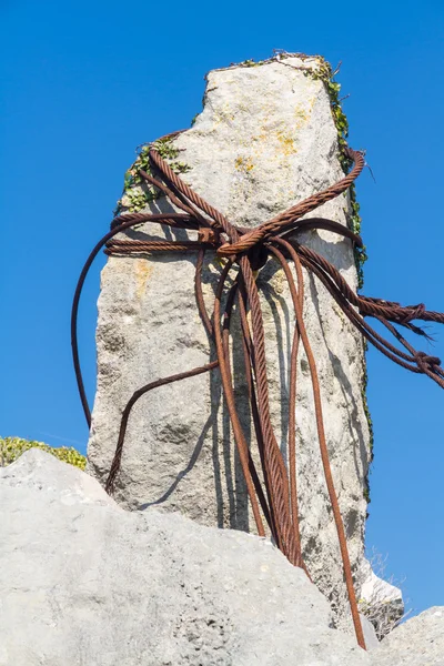 Roestig ijzer kabels lus rond kalksteen rots. — Stockfoto