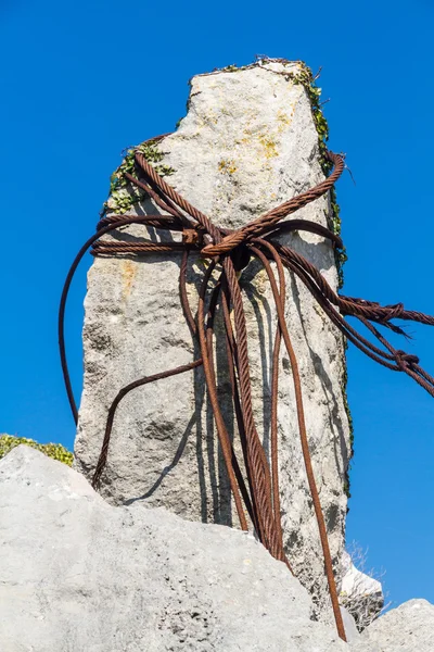 Rostige Eisenkabel um Kalksteinfelsen geschlungen. — Stockfoto