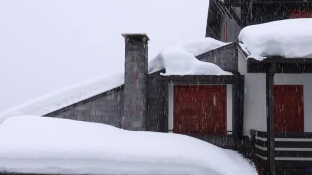 Nieve pesada cayendo sobre casa de montaña — Vídeos de Stock