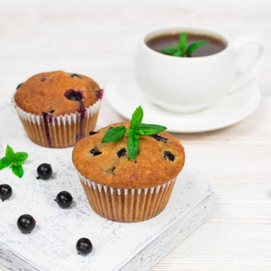 Siyah üzümlü kekler ve beyaz tabakta nane yaprakları. Yakın plan. Seçici odak.