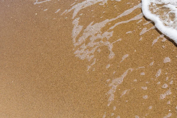 Kumlu bir sahilde yumuşak bir deniz dalgası. Yazı için yeri olan yaz arkaplanı.