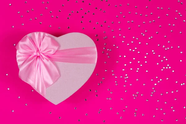 Valentines Day holiday. Pink heart box with bow on pink background. Gift heart. Love and passion concept. Valentines Day gift. Copy space. Mothers Day. View from above.