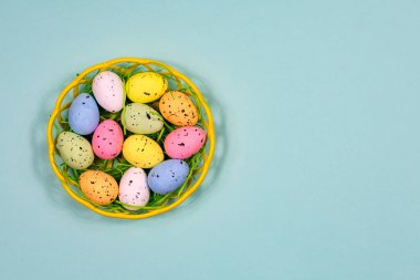 Mavi arka planda plastik bir sepette çok renkli Paskalya yumurtaları. Yazı için uygun bir yer. Yukarıdan bak. Paskalya.