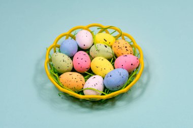 Mavi arka planda plastik bir sepette çok renkli Paskalya yumurtaları. Yakın plan. Yukarıdan bak. Paskalya.