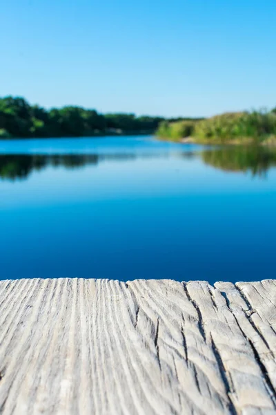 Tablero de madera envejecida sobre el telón de fondo de un paisaje con un lago claro, bosque y cañas. Severodonetsk. Lago Kleshnya. — Foto de Stock