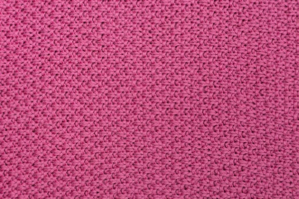 Pink knitted fabric pearl woolen background. The structure of the fabric with a natural texture. Fabric background. Knitted woolen background.