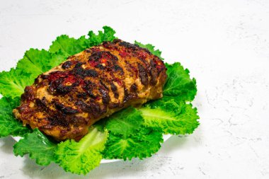 Büyük bir parça doğranmış domuz eti, fırında pişmiş, fırında pişirilmiş, yeşil marul yaprakları üzerinde, yakın plan..