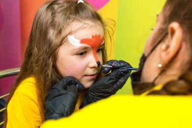 Kız, kızların yüzüne yüz boyası yapıyor..